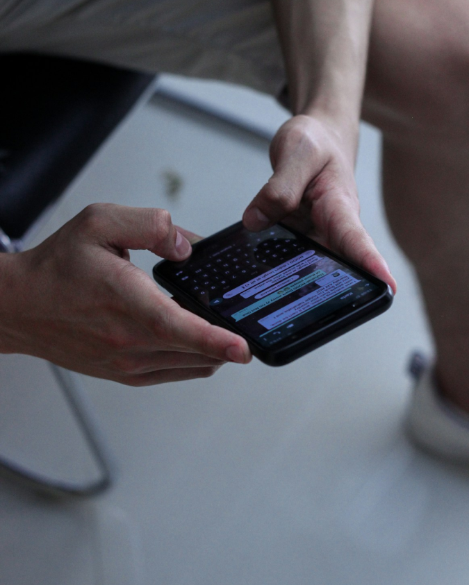 "Side view of a hand holding a juicy American cheeseburger with fresh ingredients, perfect for fast food lovers."